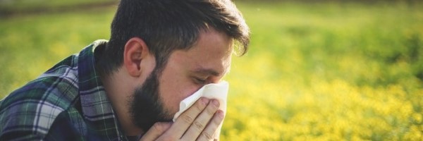 man in field blowing nose